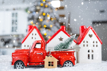 Naklejka premium Key on Christmas tree and tiny house with a red roof with Christmas decor in red retro car on table . Gift for New Year. Insurance, moving to new house, mortgage, rent and real estate