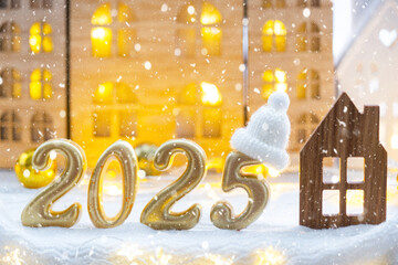 Golden figures number 2025 and tiny home on background of cozy windows of a house with warm light...