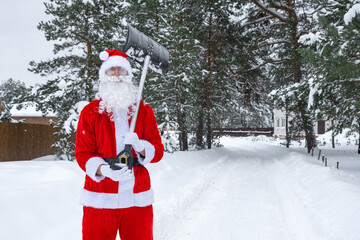 Santa Claus cleans snow with shovel in winter outdoors after a snowfall. Cleaning the streets in the village, clearing the passage for cars, difficult weather conditions for Christmas and New Year