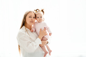 a mother with a baby daughter, a mother gently hugs her baby girl kissing, maternal love and care, a happy family with a baby on a white isolated background, a place for text
