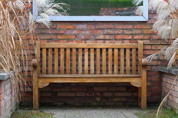 Old rustic wooden bench with brick wall in the background.