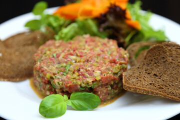 Raw meat tartare for gourmets. Raw meat tartare with spices, croutons and herbs. Beef tartare with capers. Beef tartare with bread slices.
