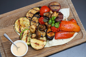 Grilled vegetables with sauce. Baked tomatoes, mushrooms, zucchini, sweet peppers and onions. Grilled vegetables are simply delicious.