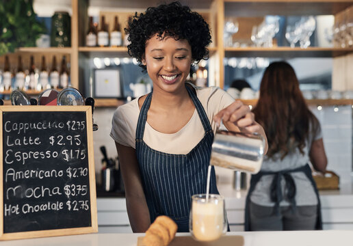Barista, woman and milk in coffee in cafe for customer order, cappuccino preparation or happy for service. Small business, waitress or smile with latte process on counter in bistro for caffeine drink