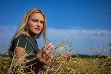 A young woman stands joyfully in a golden field beneath a beautiful blue sky, feeling free