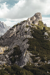 A mountain with trees and rocks under a cloudy sky