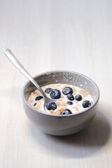 Bright and appetizing breakfast: fresh yogurt with juicy blueberries, crunchy flakes, seeds, and natural grains.