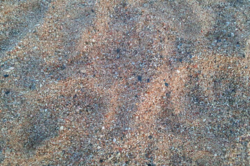 Stones and sand in the summer day. Yellow sand on the beach near a sea.