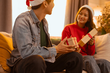 party, happy, romantic, xmas, present, friends, together, togetherness, friendship, giving. A man and a woman are sitting on a couch, both holding presents.