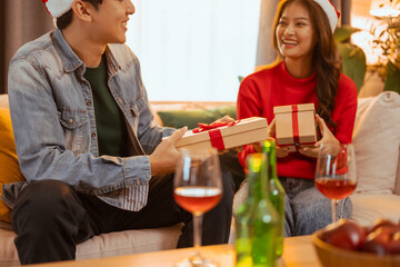 party, celebrate, anniversary, xmas, christmas, affectionate, friends, husband, happiness, together. A man and woman are sitting on a couch, They are smiling to be enjoying each other's company.