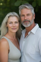 Obraz premium A couple is posing for a picture with a sandy look on their faces. The man is wearing a white shirt and the woman is wearing a silver dress