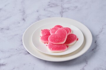 Heart-shaped marmalade on a white plate on a marble background. Valentine's Day concept.