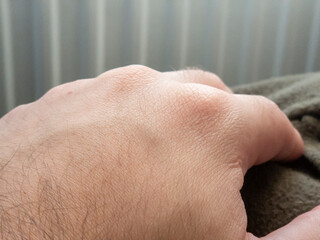 Fototapeta premium Close-up of a hand resting on a soft surface, showcasing skin texture and natural colors in a cozy setting.