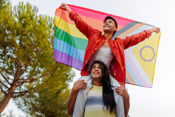 Happy non-binary couple celebrating lgbtq pride with LGBTQIA flag
