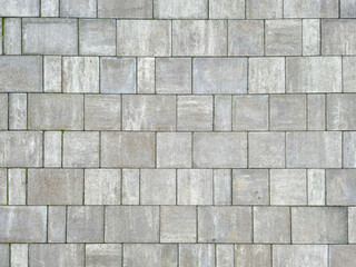 A close-up view of a textured gray paving stone surface, showcasing different shades and patterns,...