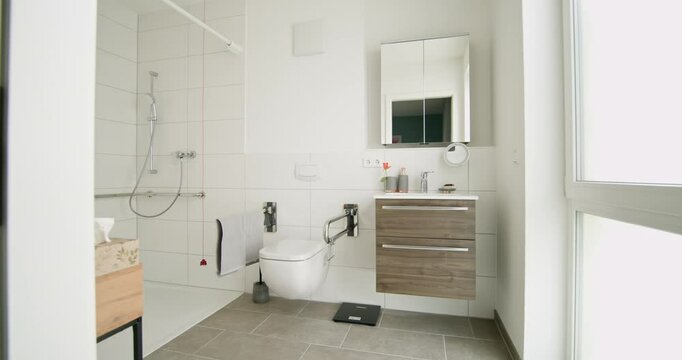 Contemporary bathroom with wheelchair accessible shower and modern vanity. White tiles and natural light create clean and bright space. Design includes accessible features for ease of use.
