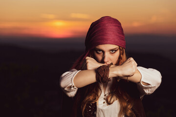 Outdoor portrait of young female in pirate costume, crossed hands. Halloween