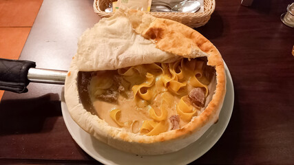 pasta with cheese and meat cooked in a frying pan and covered with a pancake