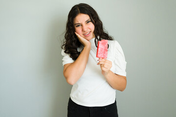 Teenage girl holding a popsicle experiencing dentin hypersensitivity and toothache in a studio