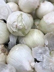 A bunch of white onions piled up in a fresh food market.