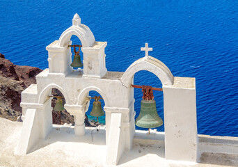 Church bells on the island of Santorini above the blue sea