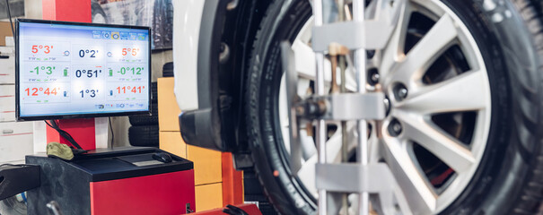 Car wheel centering machine adjustment. Auto service mechanic installing wheel alignment sensor on tire during vehicle suspension alignment adjustment