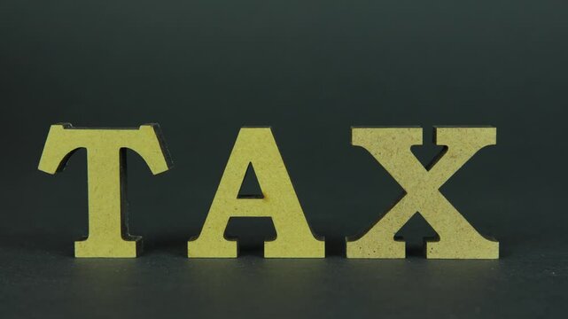 Tax payment concept. 50 cent coin rolling near word tax