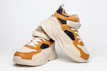 Pair of stylish beige and brown sneakers with velcro straps on white background