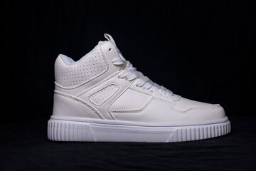 White sneaker standing on black background