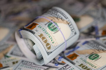 roll of US 100 dollar banknotes on 100 dollar banknotes background