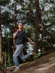 Active young woman running through a forest trail, wearing sports attire, showcasing determination and energy amidst nature s greenery Fitness and health concept