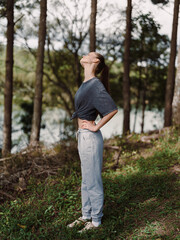 Young woman standing in nature, with head tilted back, enjoying the fresh air while wearing casual sportswear Serenity and freedom concept