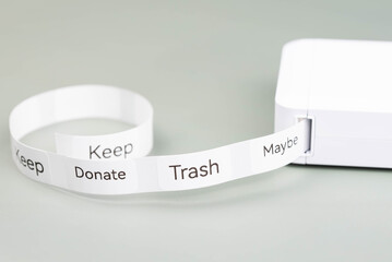 Label printer producing decluttering labels for organizing home spaces. Labels read Keep, Donate, Trash, and Maybe, as categories for effective sorting. Organized, clutter-free home environment.