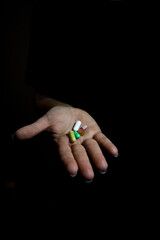 On a black background, a hand with pills, suggestion to take medication. Treatment of diseases