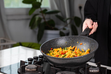 Close up of Chef cook hands cooking and toss roasted pasta, onion, pepper, carrot, vegetables, mushrooms, green peas, beans, garlic in frying wok pan on gas stove. Flying food levitation.