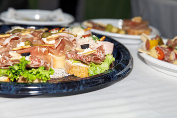Gourmet meat and cheese platter with fresh vegetables and olives on rustic bread