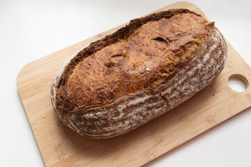 Loaf of sourdough bread on wooden chopping board. White background. Select focus.
