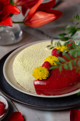 Cake yellow and red colour with raspberries and flowers on a plate