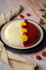 Cake yellow and red colour with raspberries and flowers on a plate