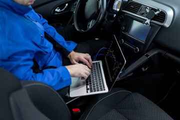 Technician working on a laptop in a car, troubleshooting electronic issues during an evening in an urban setting