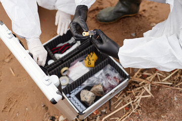 Top view closeup of two unrecognizable scientists wearing hazmat suits and holding test tube with water in gloved hands while doing probes outdoors, copy space