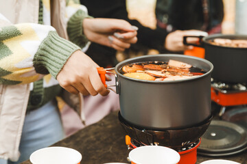 Delicious hot mulled wine in a pan on the stove, close-up. A girl prepares mulled wine at a picnic.