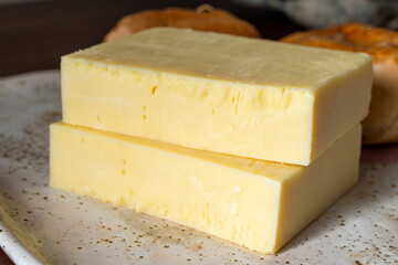 Block of aged cheddar cheese, the most popular type of cheese in United Kingdom and USA, natural cheese from cow milk