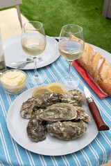 Plate with fresh live oysters with citron, bread, butter and white wine served at restaurant in oyster-farming village, Arcachon bay, Gujan-Mestras port, France