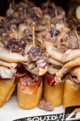 Typical snacks of Basque Country, pinchos or pinxtos skewers with small pieces of bread, fish, sea food, sweet green pepper served in bar in San-Sebastian or Bilbao, Spain