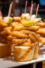Typical snacks of Basque Country, pinchos or pinxtos skewers with small pieces of bread, fish, sea food, sweet green pepper served in bar in San-Sebastian or Bilbao, Spain