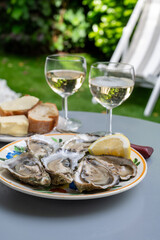 Plate with fresh live oysters with citron, bread, butter and white wine served at restaurant in oyster-farming village, Arcachon bay, Gujan-Mestras port, France