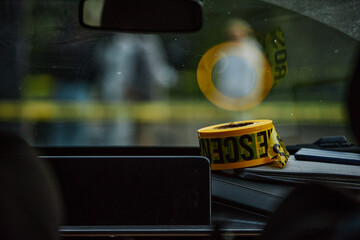 Roll of yellow Crime scene tape on dashboard of modern police car with reflection in windshield mirror, copy space © Seventyfour