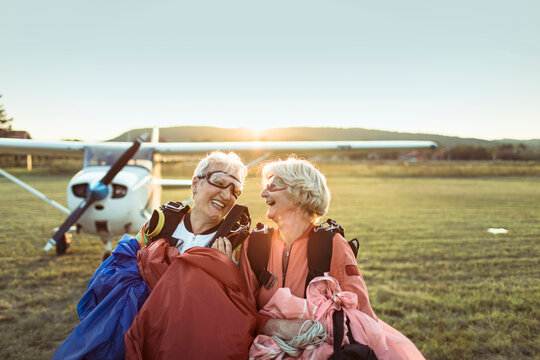 Two senior women laughing after skydiving adventure at sunset