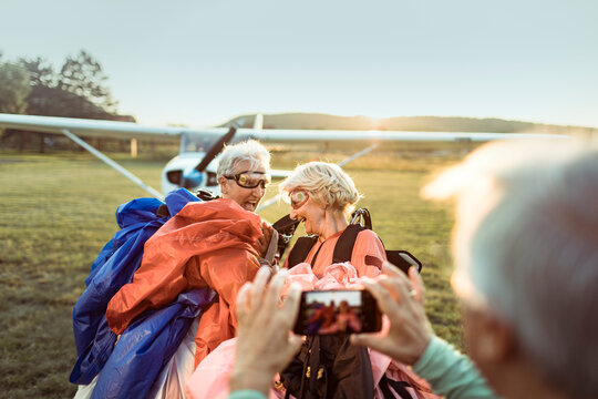 Two senior women laughing after skydiving adventure at sunset